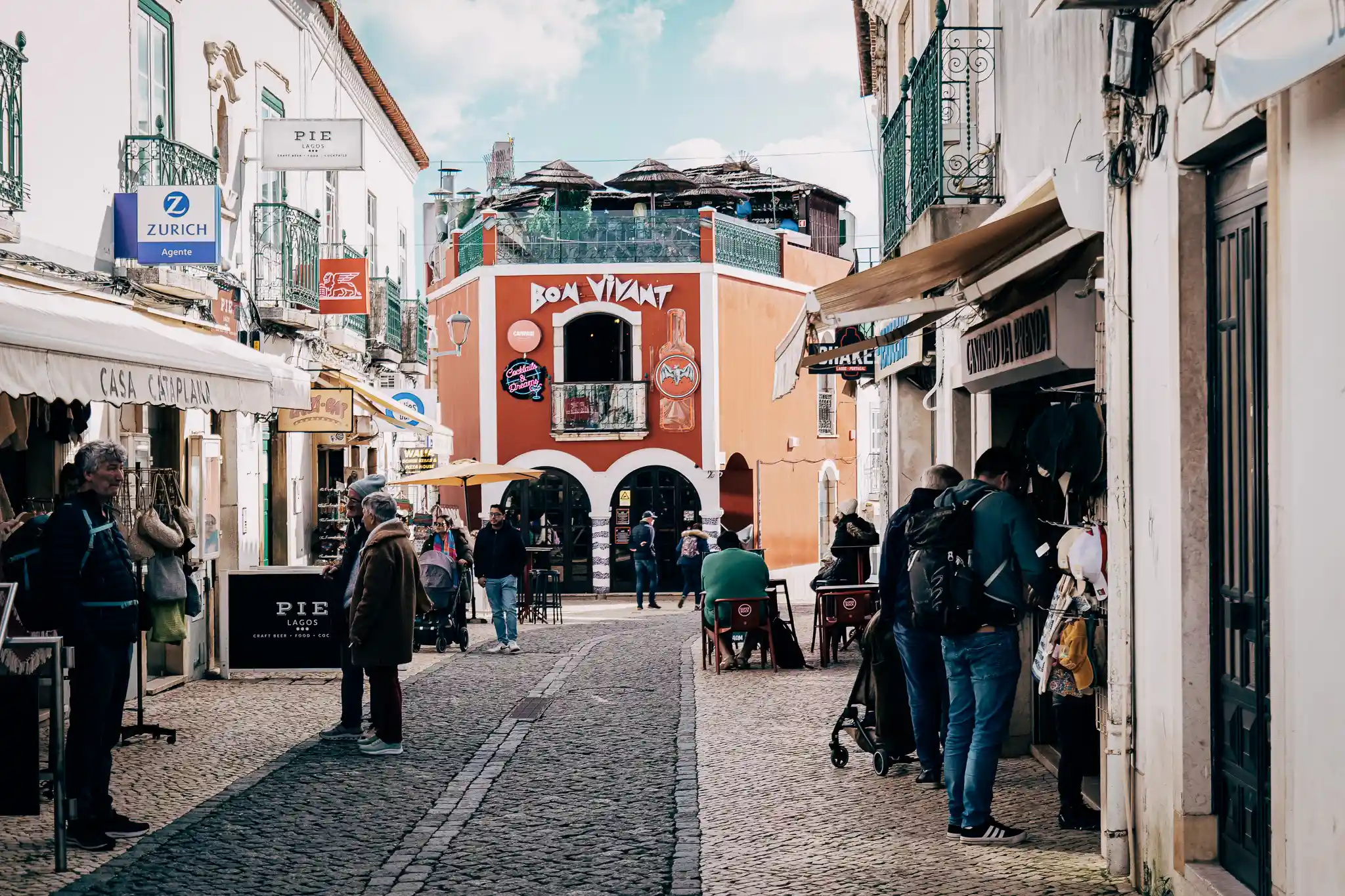 Rue animée de Lagos, Portugal, avec boutiques et restaurants, ambiance conviviale et architecture traditionnelle.